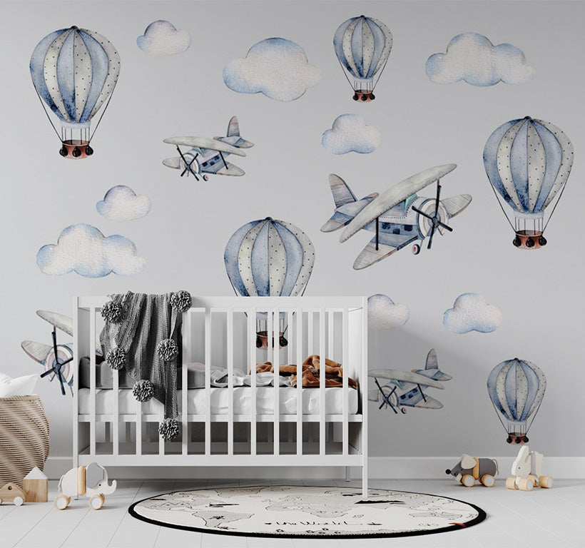 a whimsical pattern of vintage airplanes and hot air balloons in shades of blue and white, floating amongst soft, fluffy clouds. The hand-drawn watercolor style gives the design a nostalgic and playful feel, perfect for a dreamy or travel-themed aesthetic. The repeating elements create a charming, serene atmosphere.