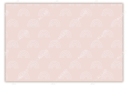 A soft blush-colored background adorned with a repeating pattern of white, dotted rainbows. The delicate pastel tones and minimalistic design create a calm and playful aesthetic, ideal for nurseries or children's rooms. The symmetrical layout adds to the overall soothing appeal.